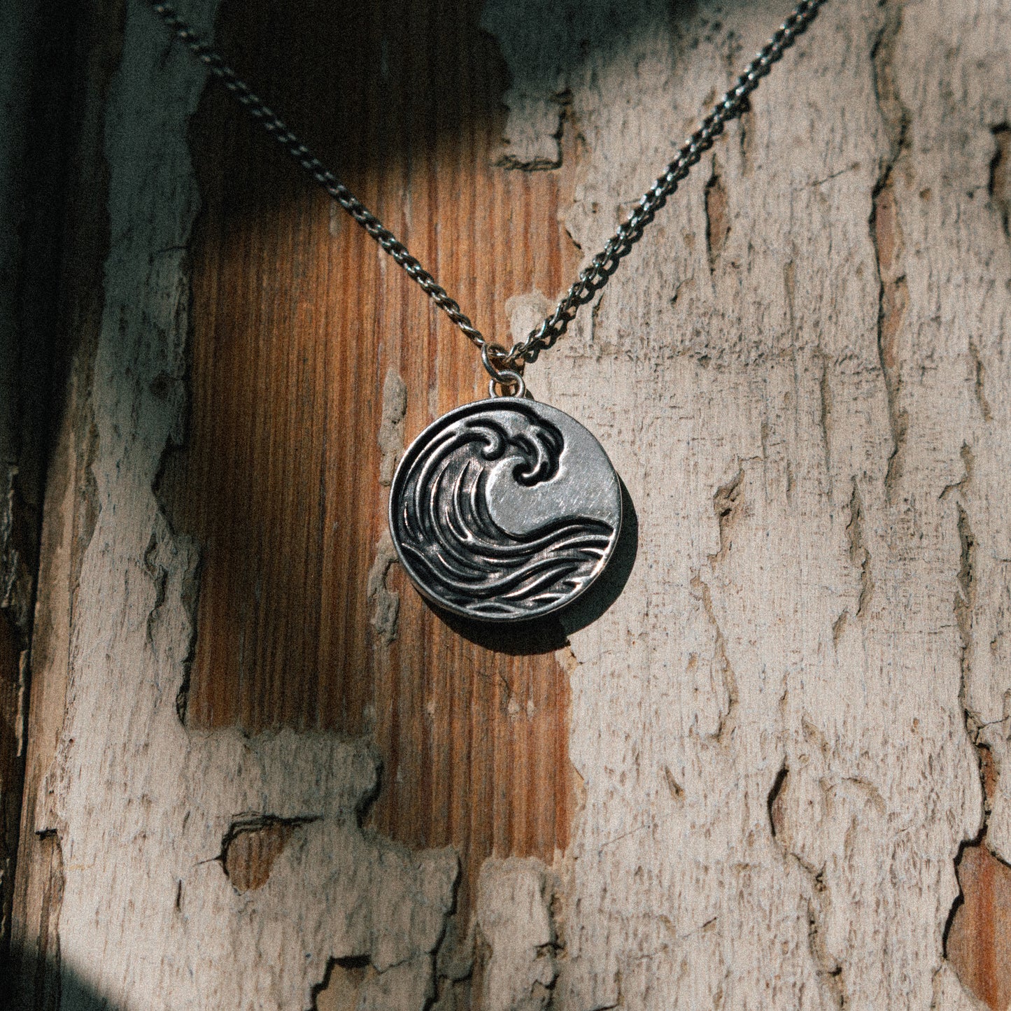 Solaque Ocean Drift handmade sterling silver wave design pendant jewellery on a rustic wooden surface