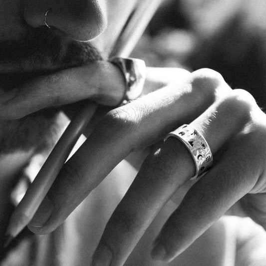 Solaque Wanderer's Script handmade sterling silver icon design ring jewellery on hand, holding a pencil