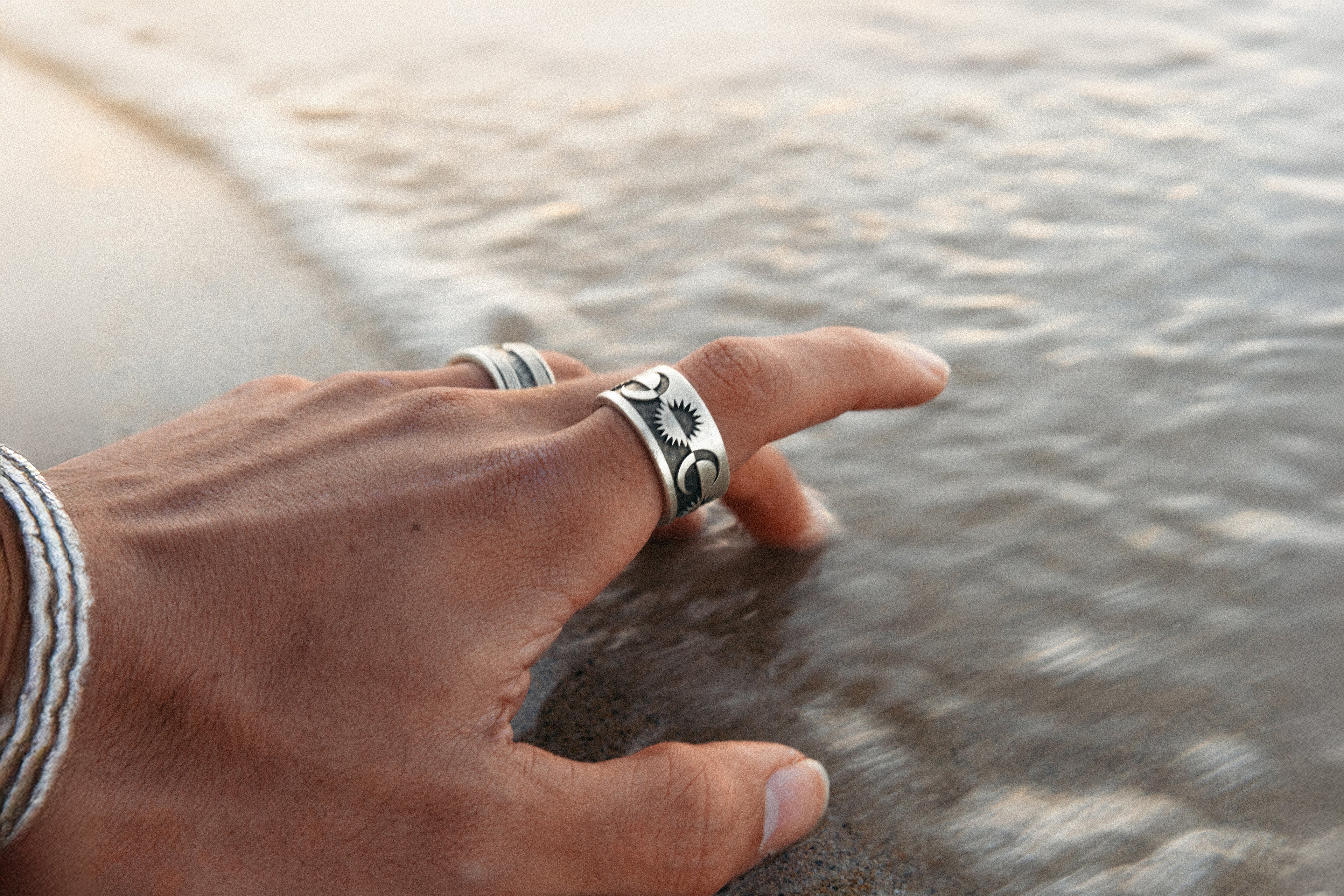 Solaque handmade sterling silver jewellery wearing on hand touching the sea