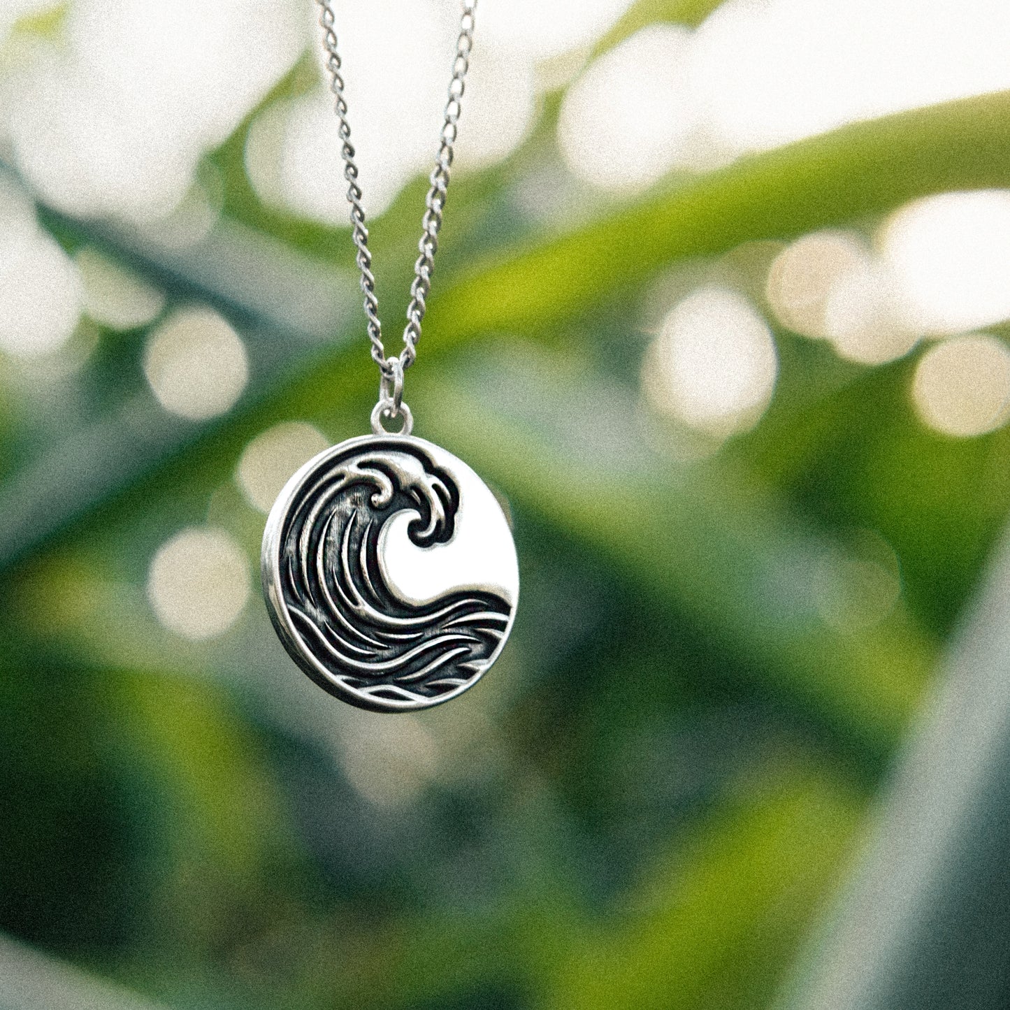 Solaque Ocean Drift handmade sterling silver wave design pendant jewellery against a natural background