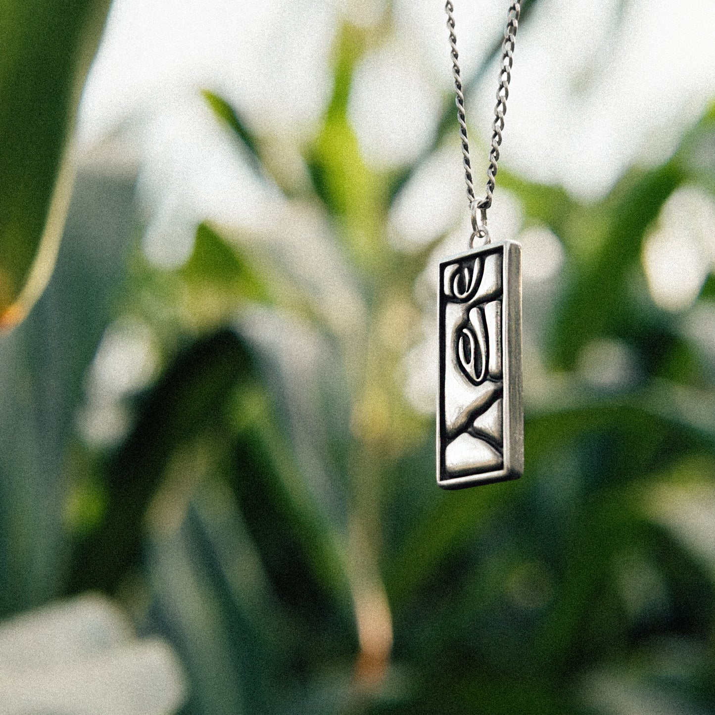 Solaque Silent Gaze handmade sterling silver face design pendant jewellery against a natural background