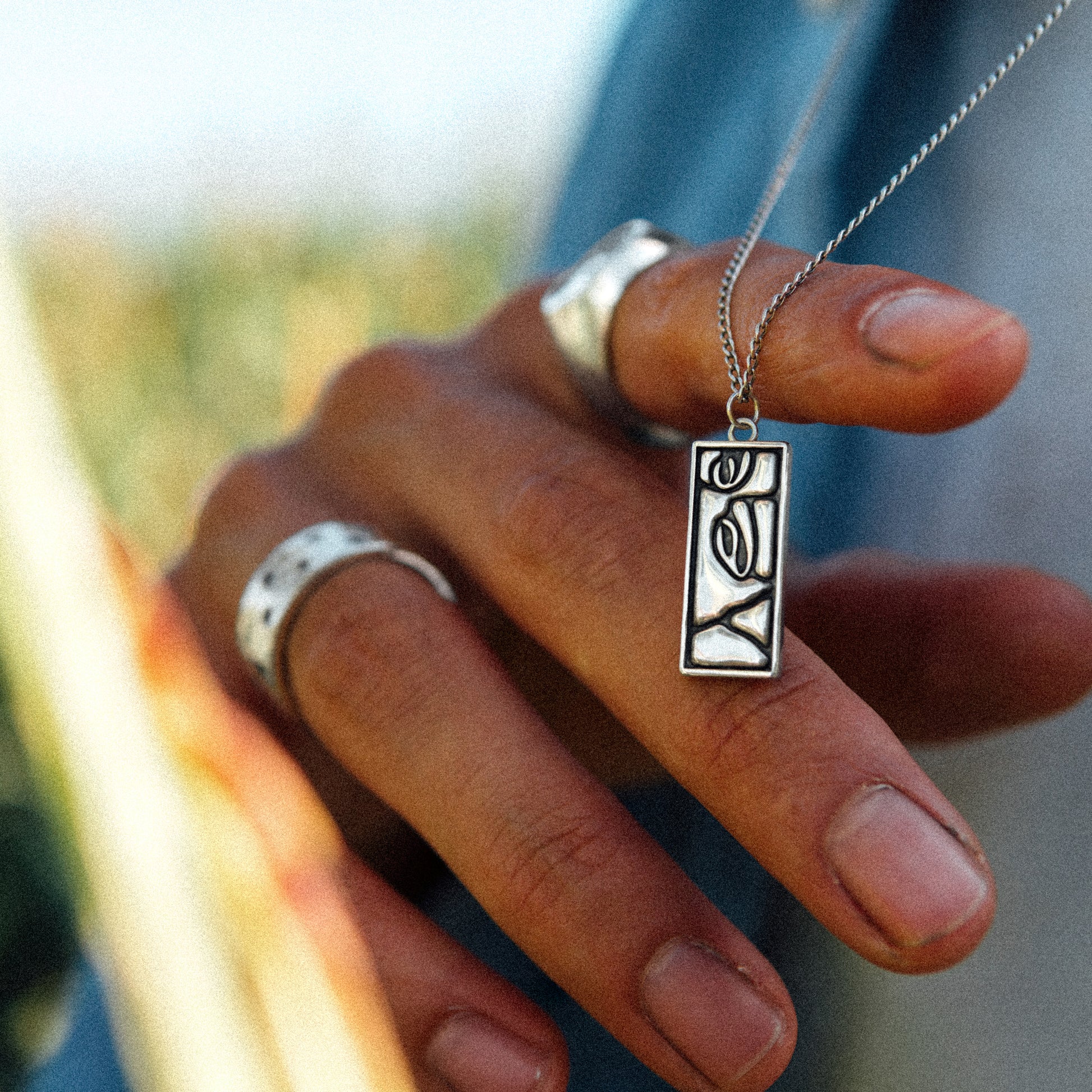 Solaque Silent Gaze handmade sterling silver face design pendant jewellery held against fingers