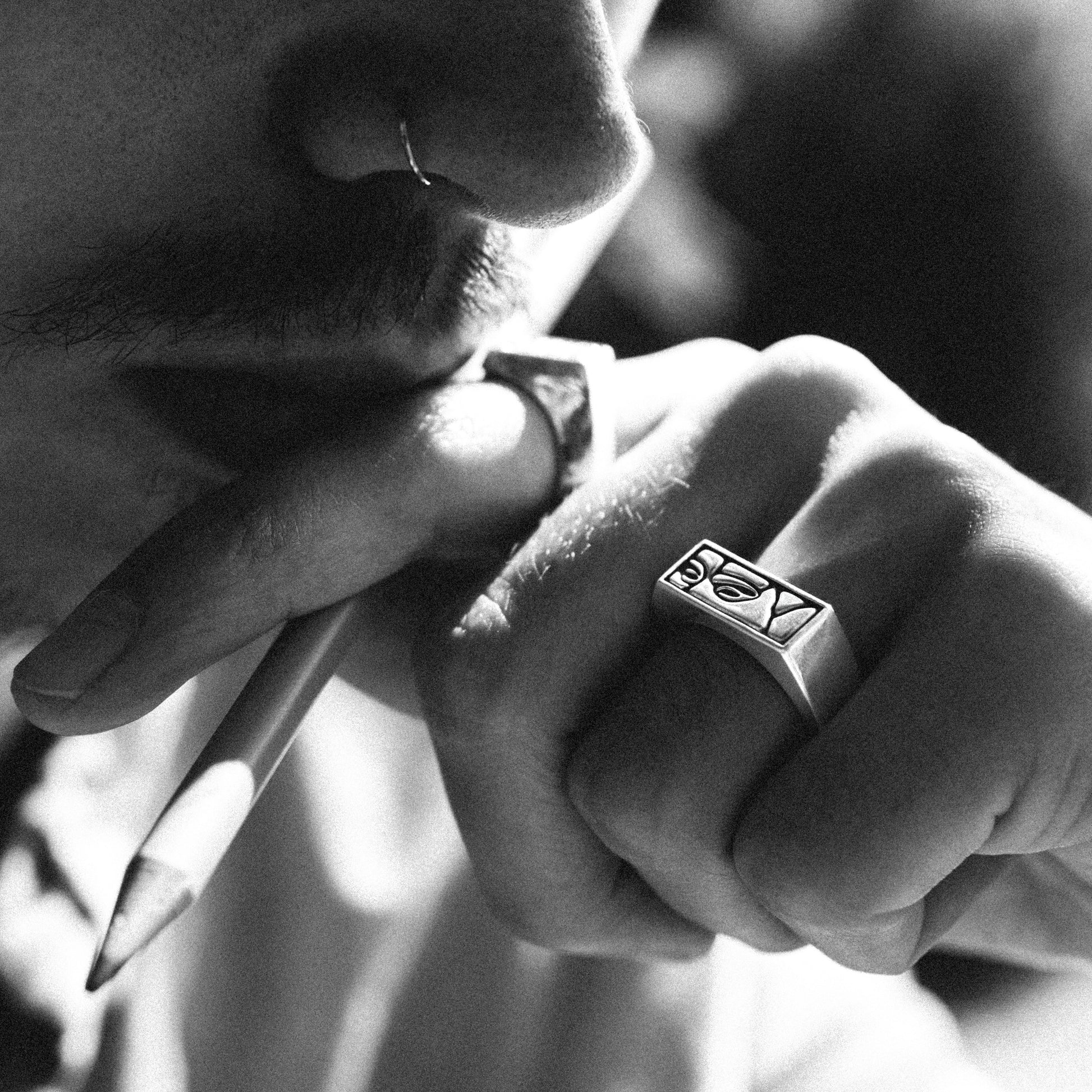 Solaque Silent Gaze handmade sterling silver face design ring jewellery on hand, holding a pencil