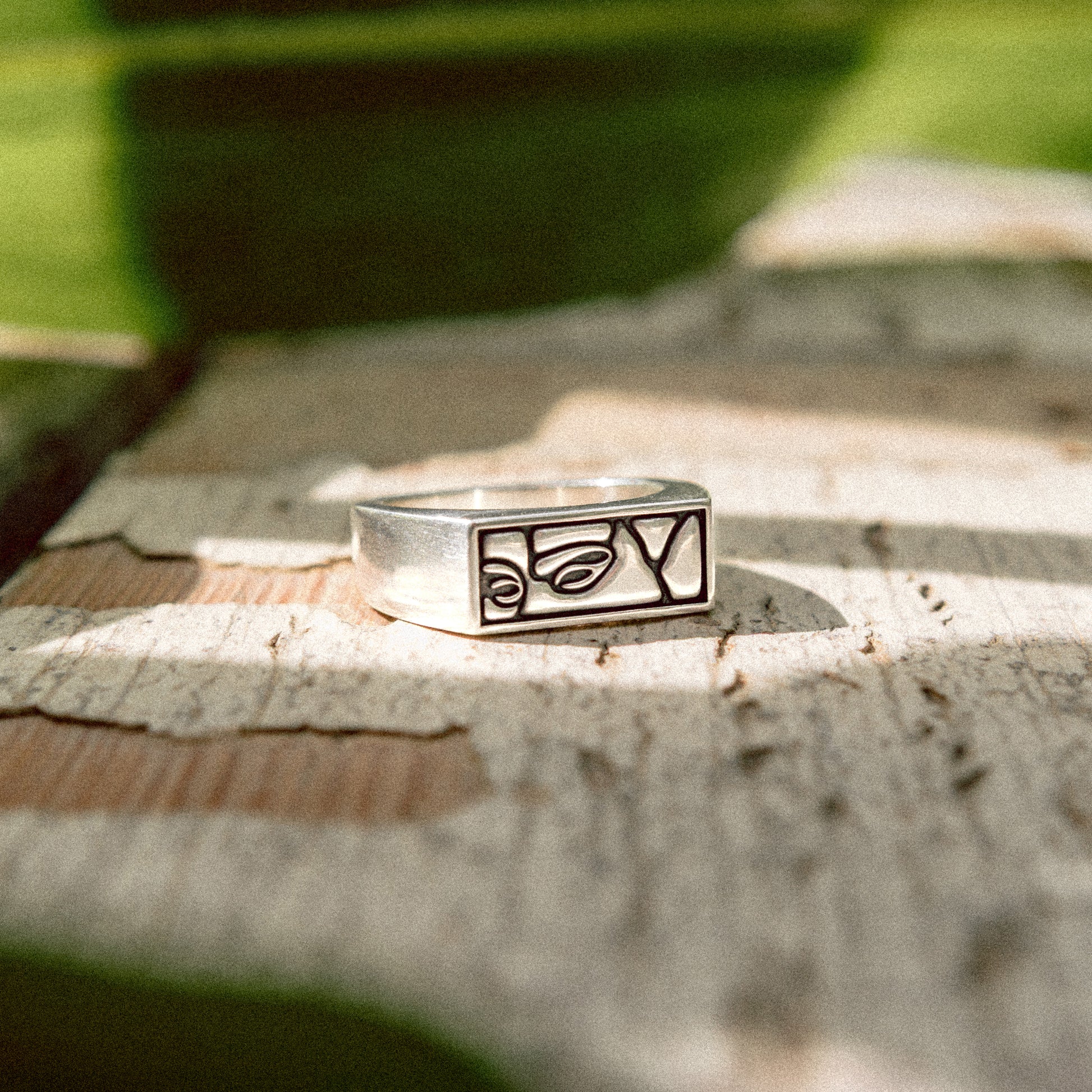 Solaque Silent Gaze handmade sterling silver face design ring jewellery on a rustic wooden surface