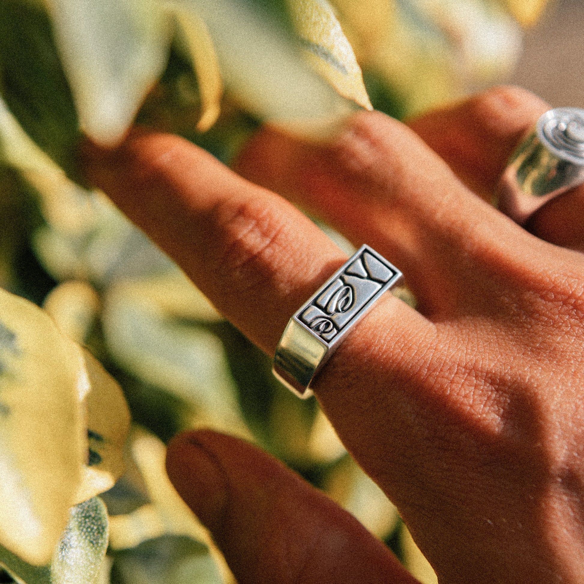Solaque Silent Gaze handmade sterling silver face design ring jewellery on hand against a natural background