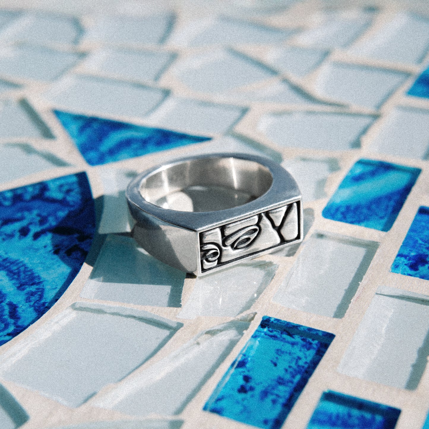 Solaque Silent Gaze handmade sterling silver face design ring jewellery on a mosaic tile surface