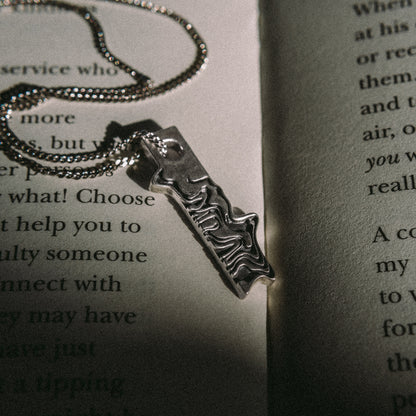 Solaque Tidal Motion handmade sterling silver pendant jewellery on book