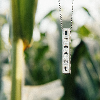 Solaque Wanderer's Script handmade sterling silver icon design pendant jewellery against a natural background