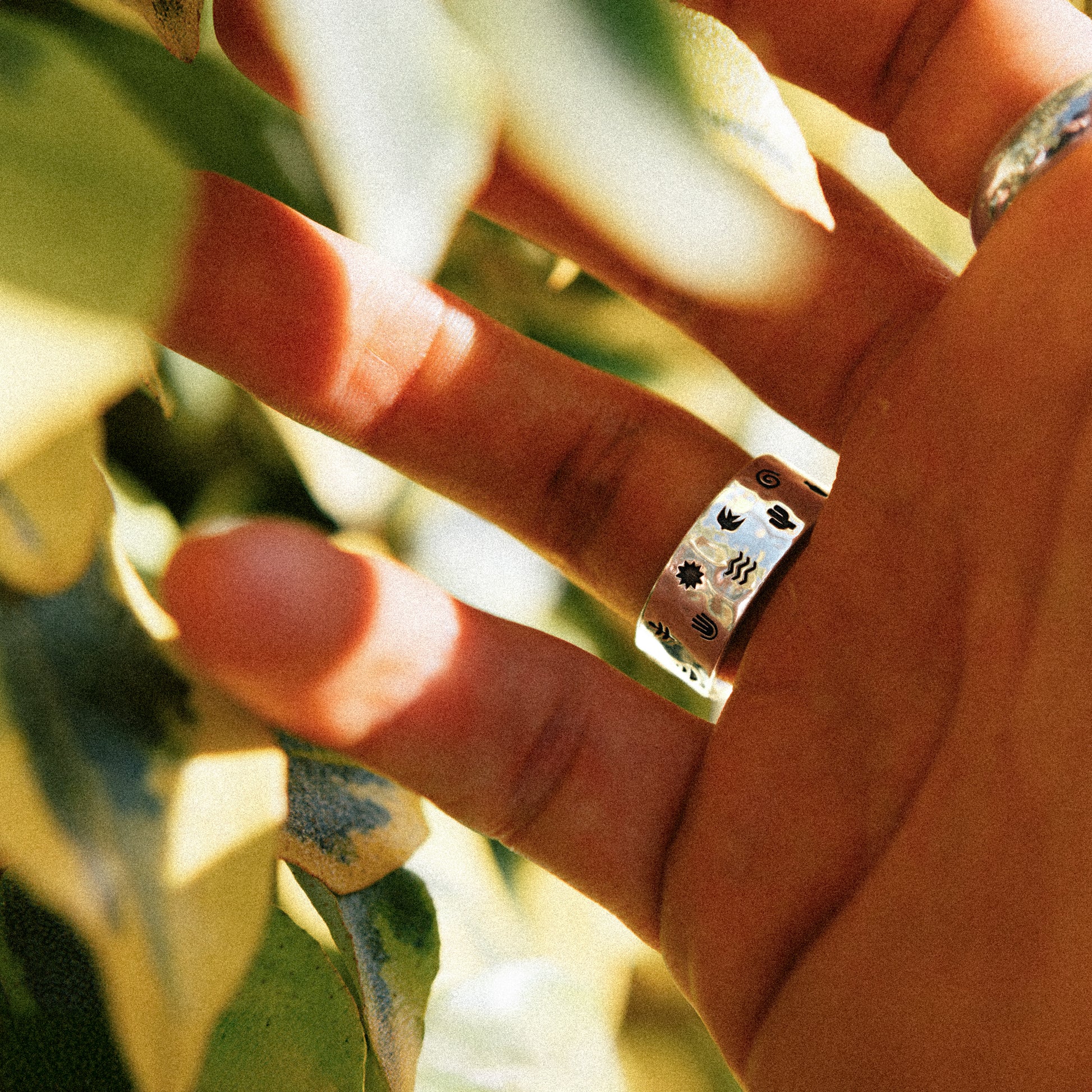 Solaque Wanderer's Script handmade sterling silver icon design ring jewellery on hand against a natural background
