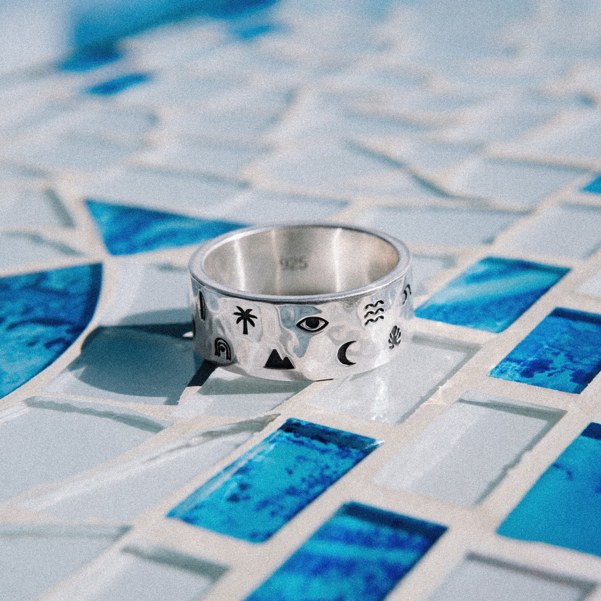 Solaque Wanderer's Script handmade sterling silver icon design ring jewellery  on a mosaic tile surface